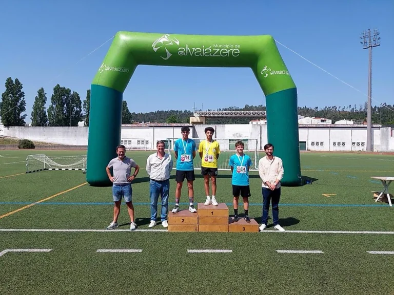 Três alunos com medalhas no pódio de atletismo, junto a um arco insuflável do Município de Alvaiázere.