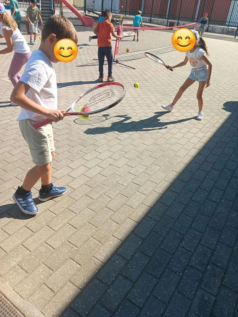 Alunos com raquetes de ténis e bolas no recreio do Centro Escolar de Avelar; em primeiro plano, um aluno de t-shirt branca.